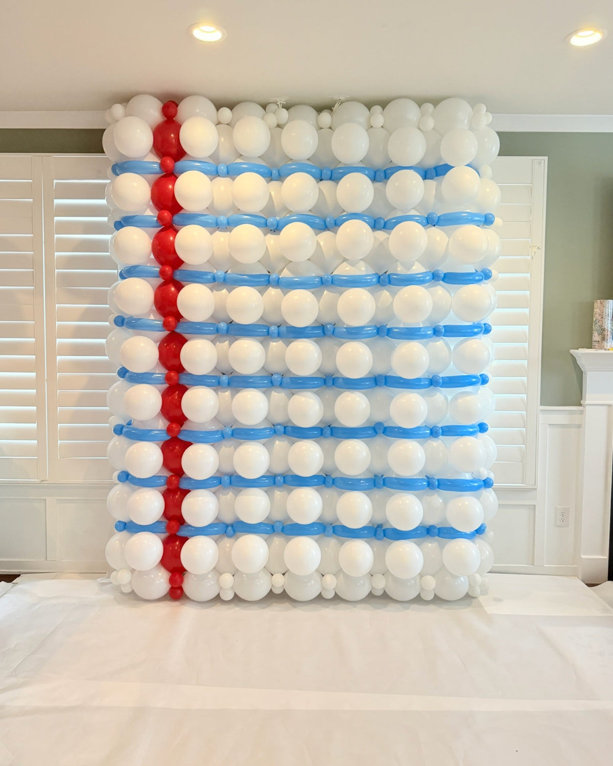 Back-to-school balloon wall styled as notebook paper with white balloons, blue ruled lines, and a red vertical margin.