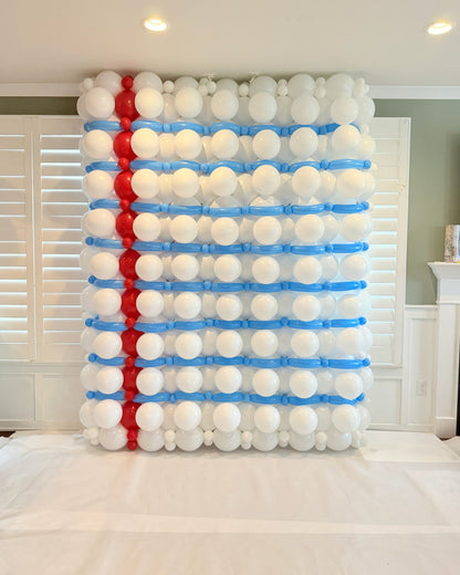 Back-to-school balloon wall styled as notebook paper with white balloons, blue ruled lines, and a red vertical margin.