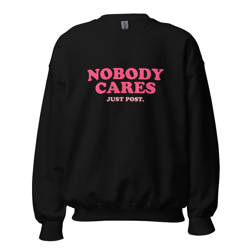 Black sweater featuring the phrase "Nobody Cares, Just Post" in bold pink and white lettering, perfect for content creators and casual wear.