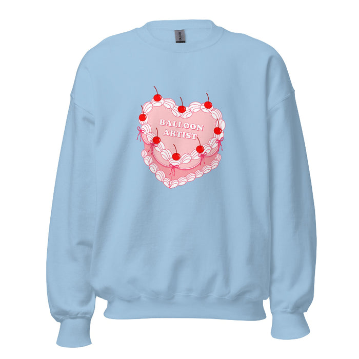 light blue sweater featuring a vintage-inspired heart cake design with cherries, white piping details, and the text "Balloon Artist" in the center.