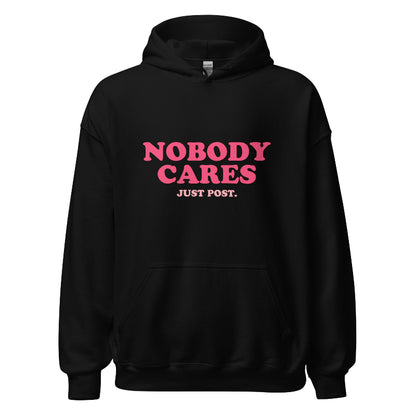 Black hoodie featuring the phrase "Nobody Cares, Just Post" in bold pink and white lettering, perfect for content creators and casual wear.