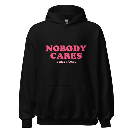 Black hoodie featuring the phrase "Nobody Cares, Just Post" in bold pink and white lettering, perfect for content creators and casual wear.